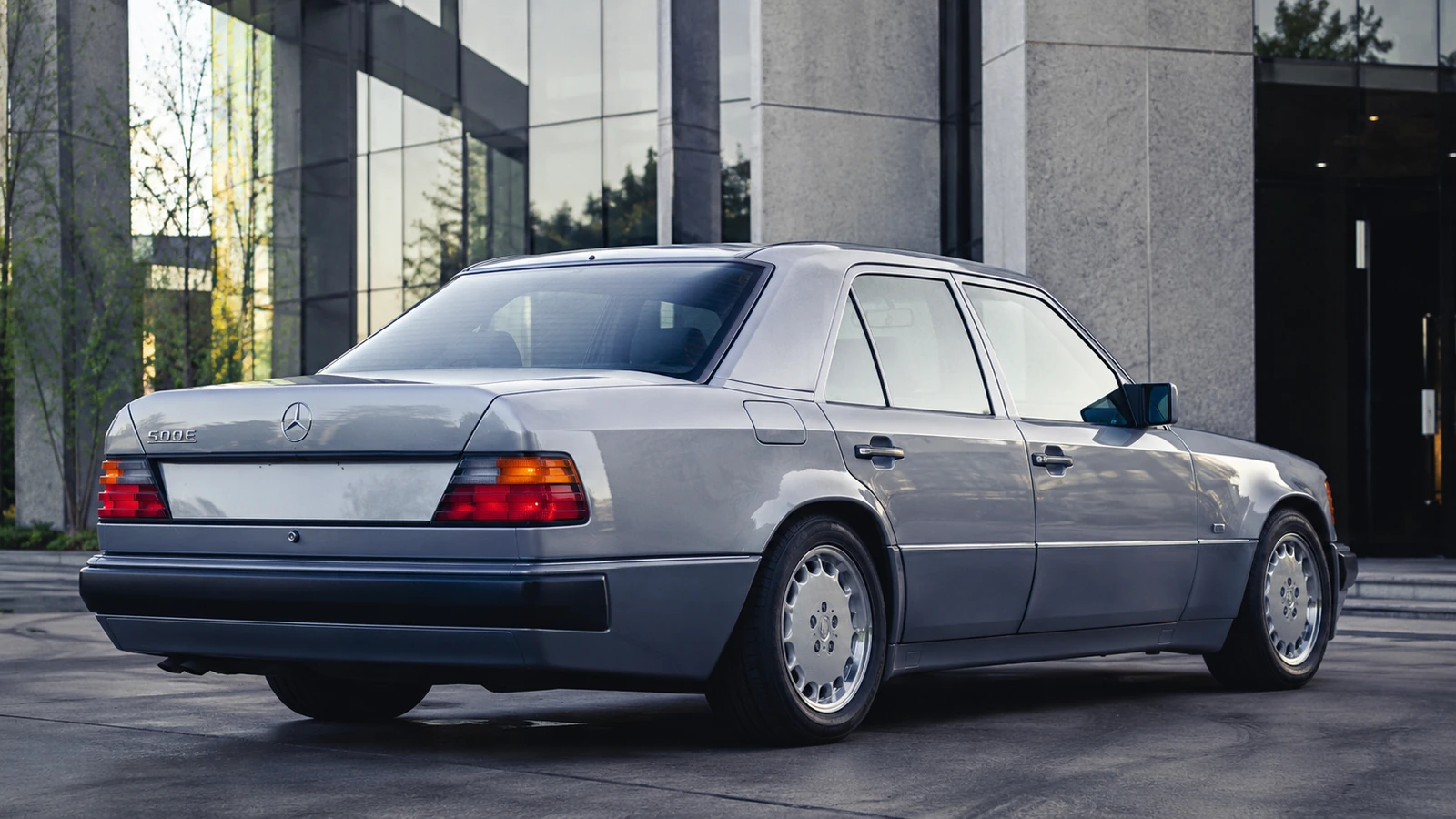 АВТО 1000702 серебристый Mercedes 500 E у делового центра в стиле 90-х