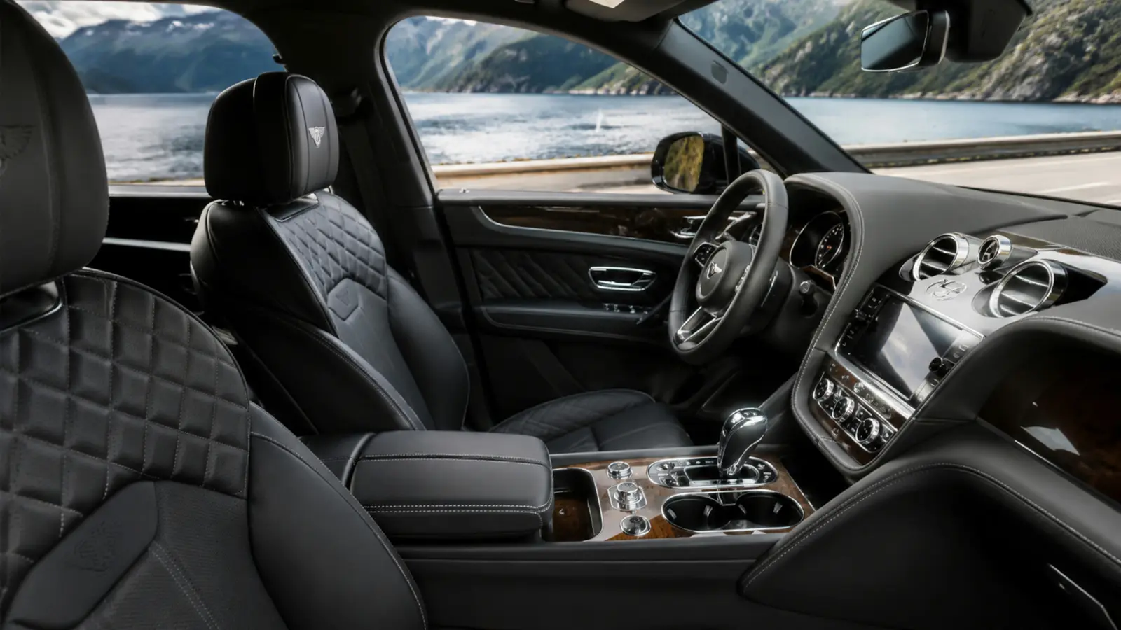 АВТО 1003029 чёрный Bentley Bentayga передние кресла и центральная консоль крупным планом на дороге вдоль фьорда