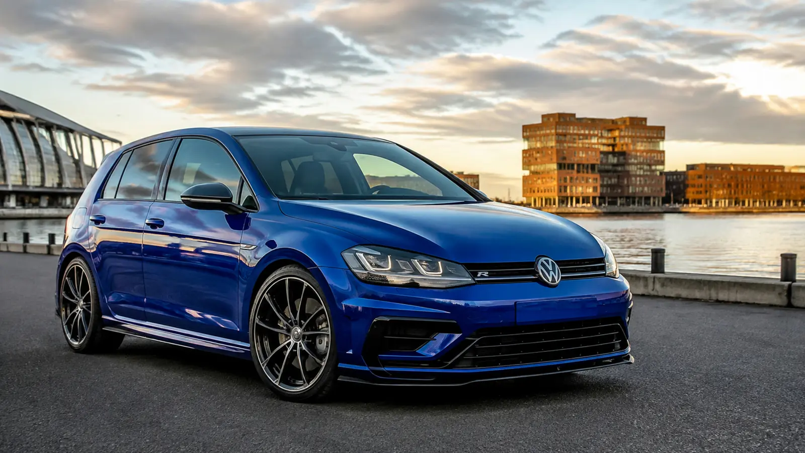 АВТО 1003054 синий Volkswagen Golf R крупно общий ракурс с выразительной архитектурой на набережной большого города