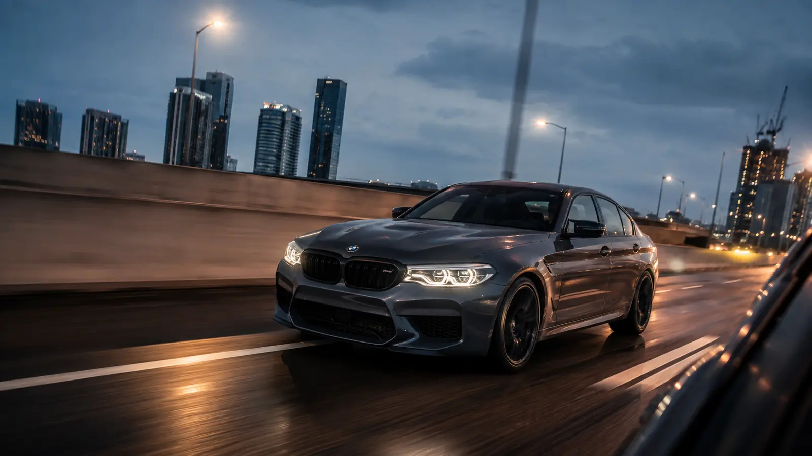 АВТО 1001962 графитовый BMW M5 в движении на городской магистрали
