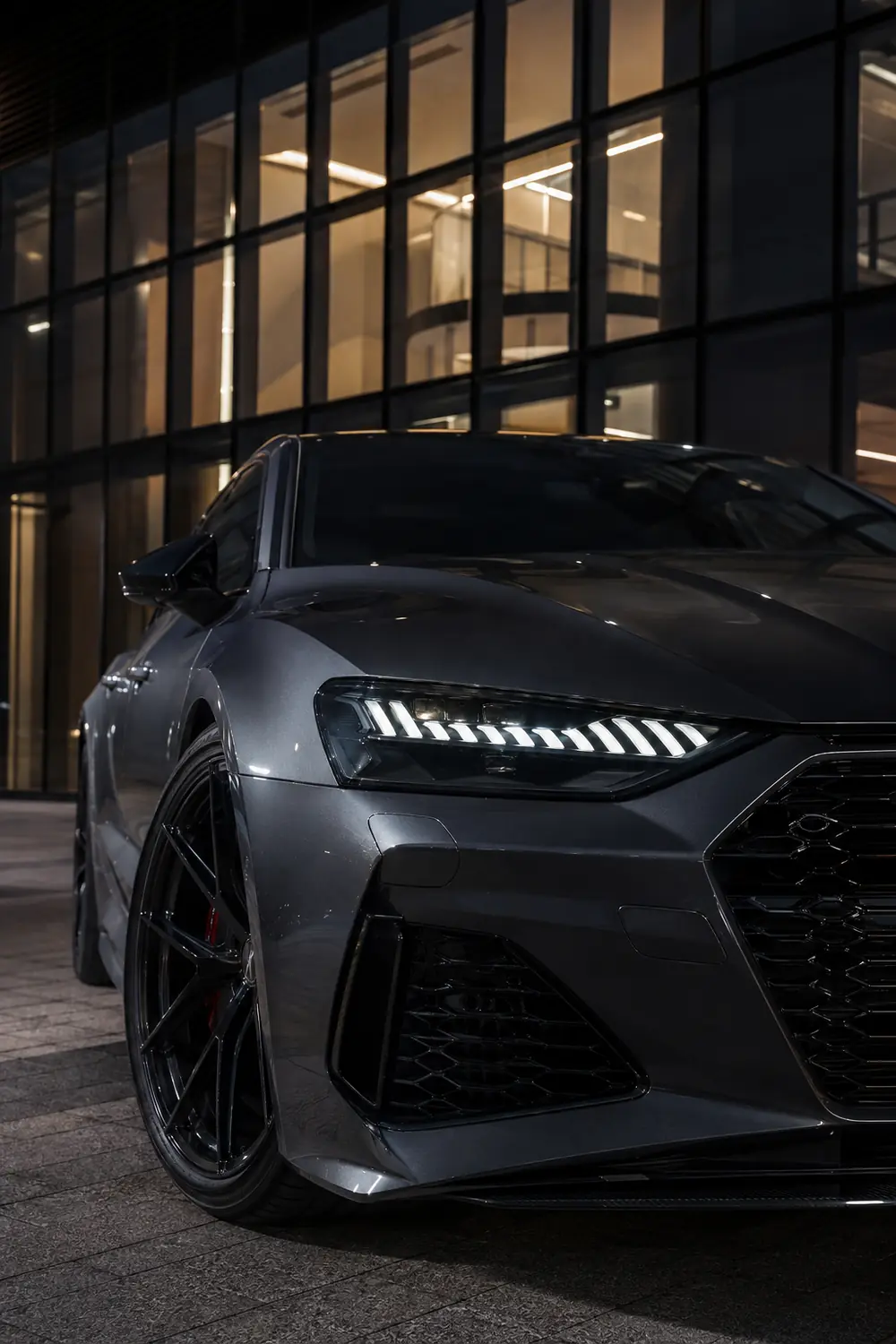 АВТО 1003755 лицо фар серого Audi RS7 в вечерней архитектуре