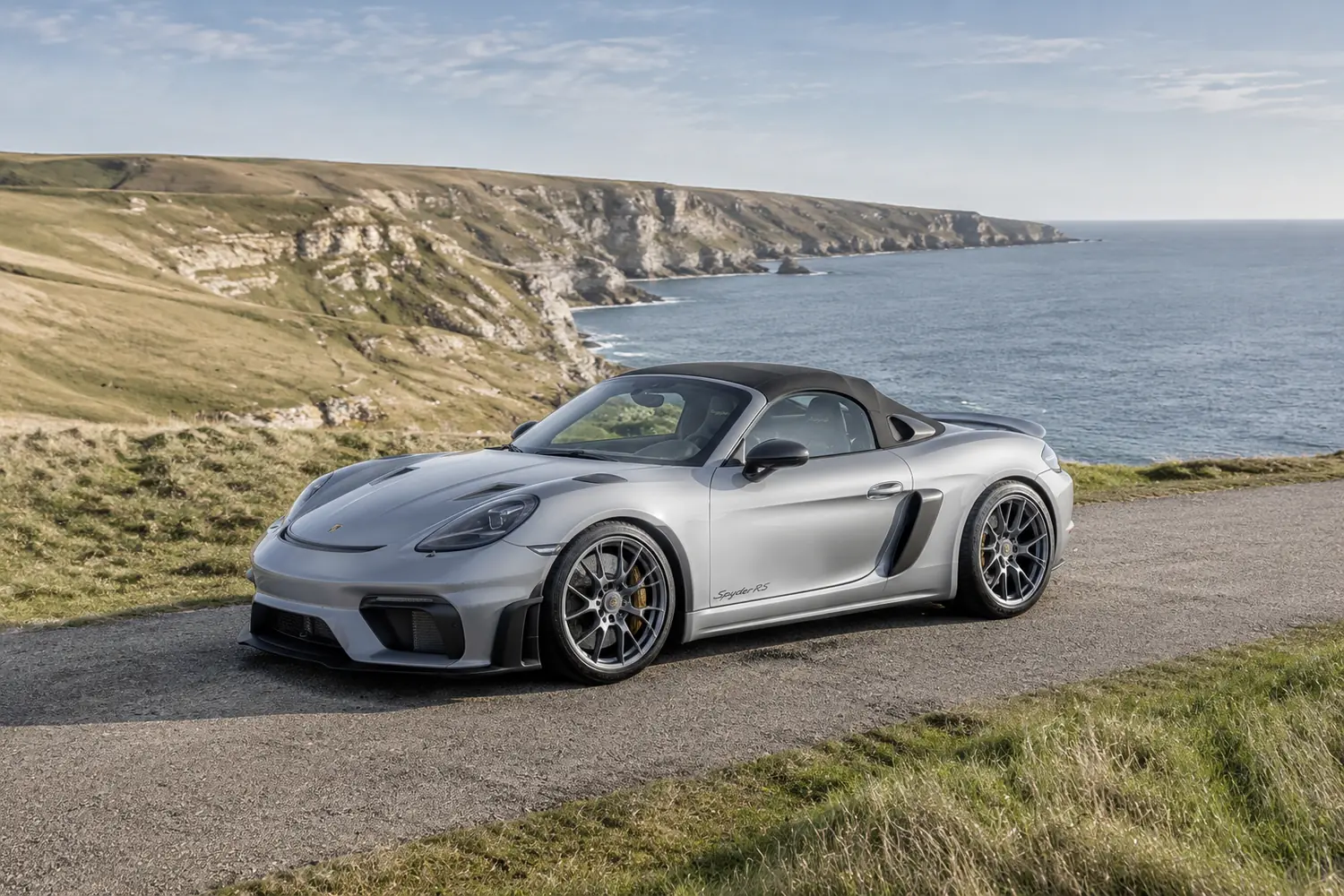 АВТО 1003822 серебристый Porsche 718 Spyder RS на дороге у скал
