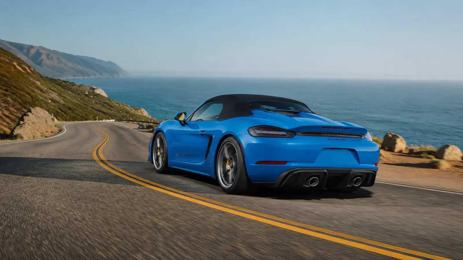 АВТО 1000971 синий Porsche 718 Spyder на океанской дороге