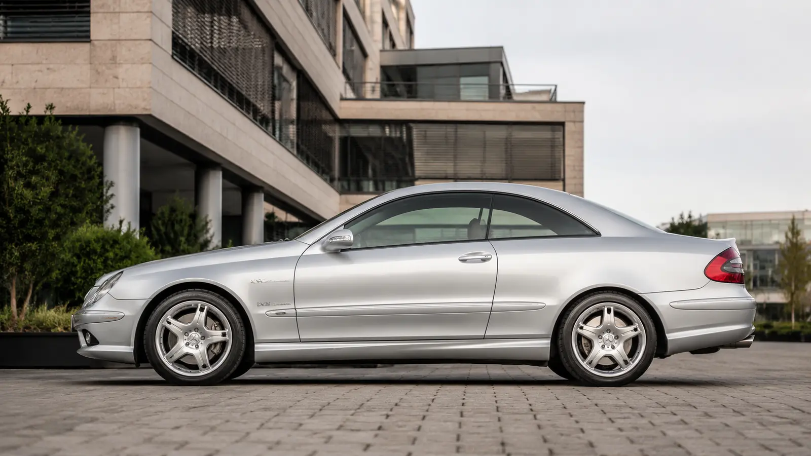 АВТО 1000878 серебристый Mercedes CLK 55 у европейского офиса 2000-х