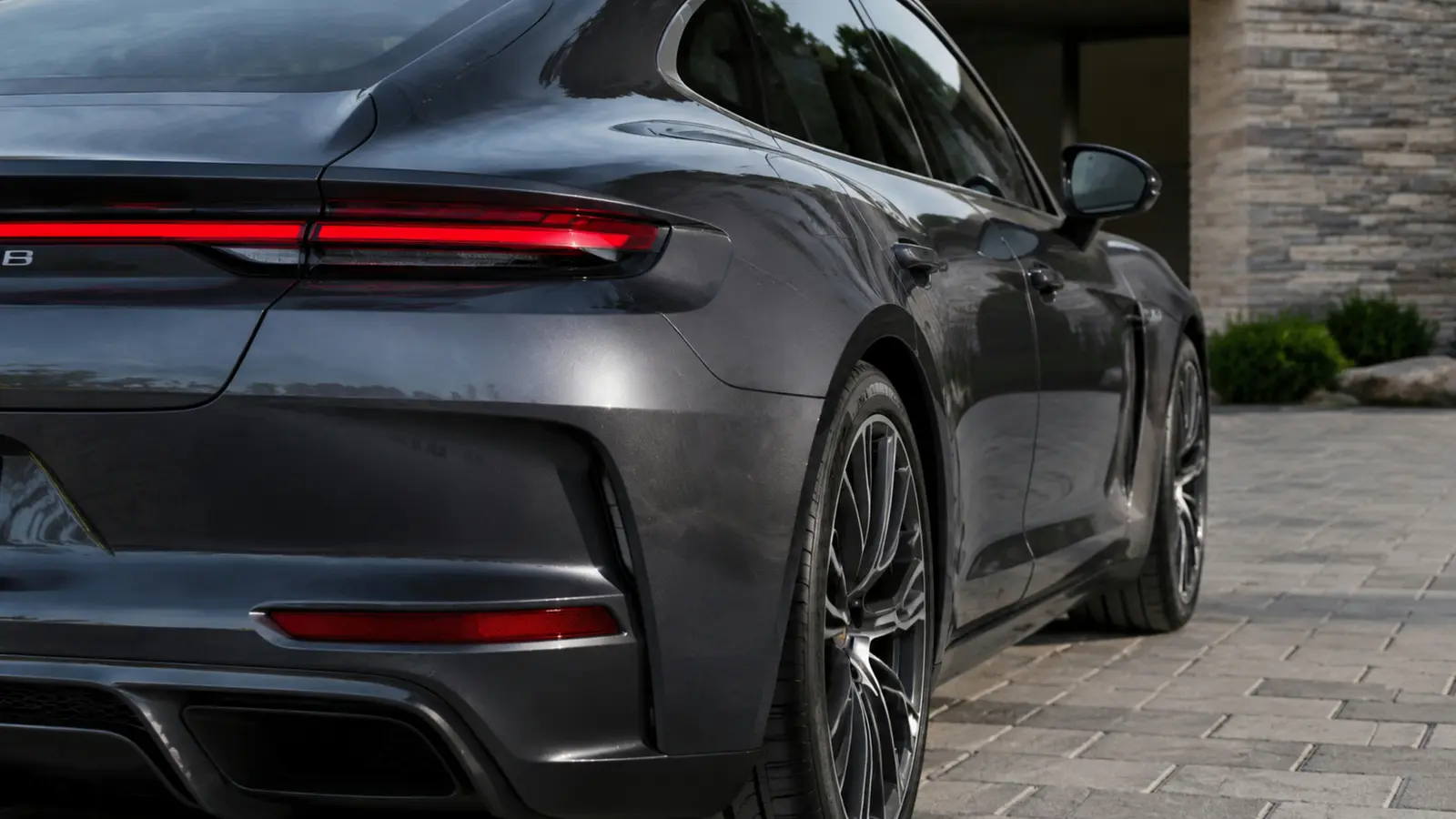 АВТО 1003088 графитовый Porsche Panamera Turbo задний фонарь и линия кузова крупным планом в современном каменном дворе