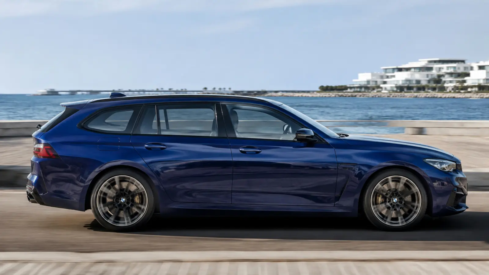 АВТО 1002798 синий BMW M5 Touring крупным профилем у современной набережной