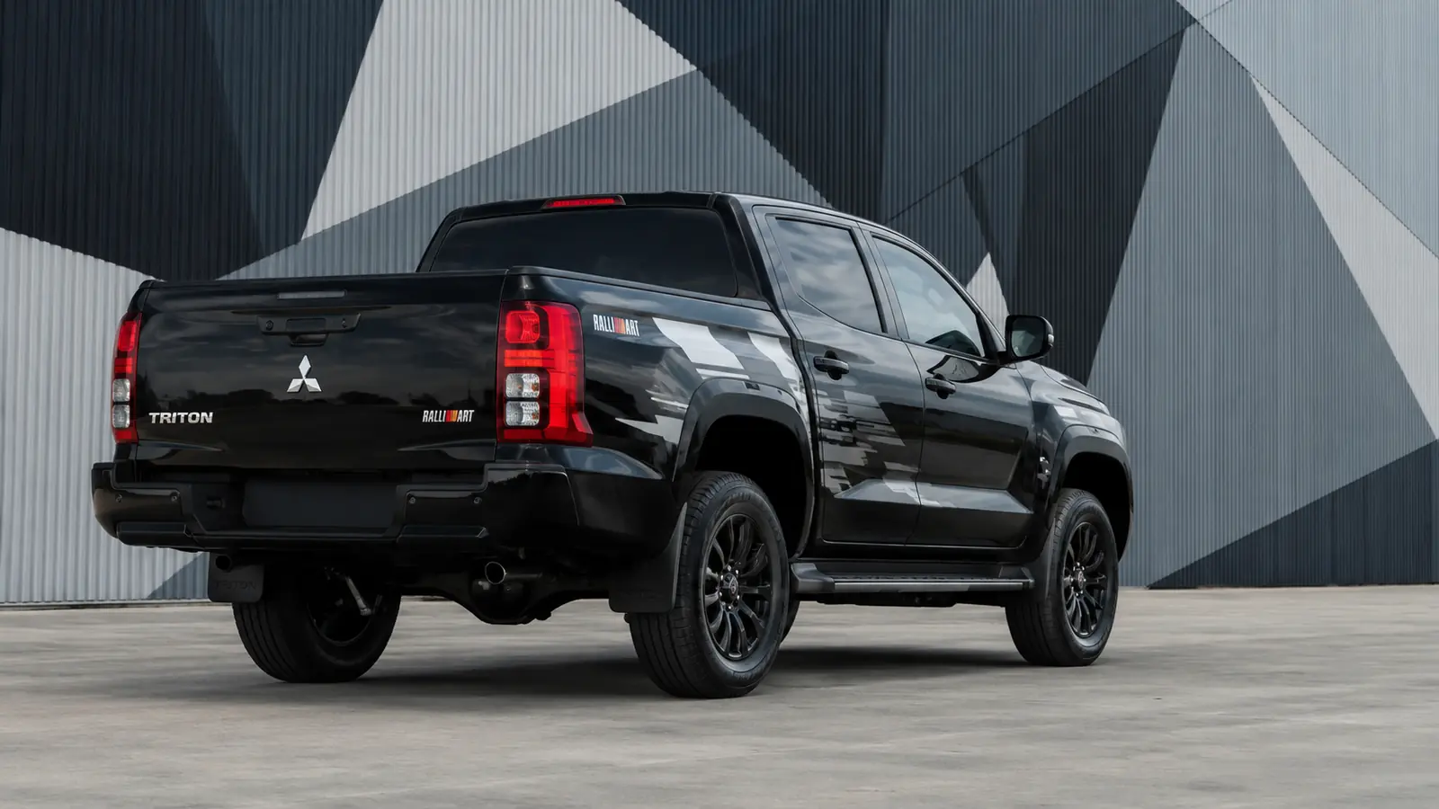 АВТО 1002731 чёрный Mitsubishi Triton Ralliart крупно у геометричного фасада