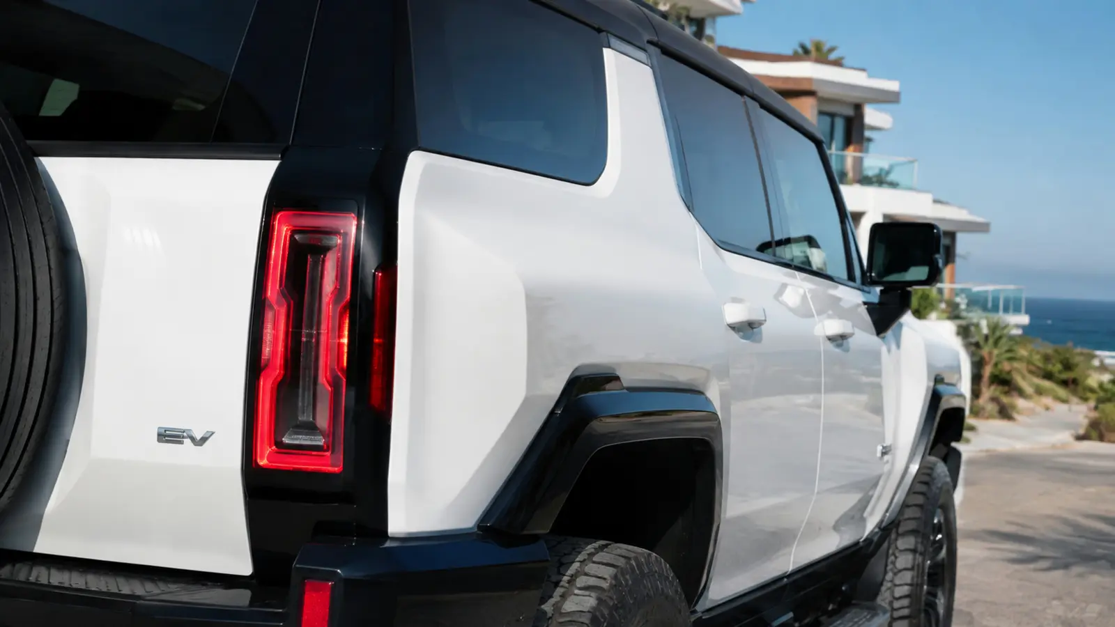 АВТО 1003051 белый GMC Hummer EV задний фонарь и линия кузова крупным планом в солнечном приморском квартале