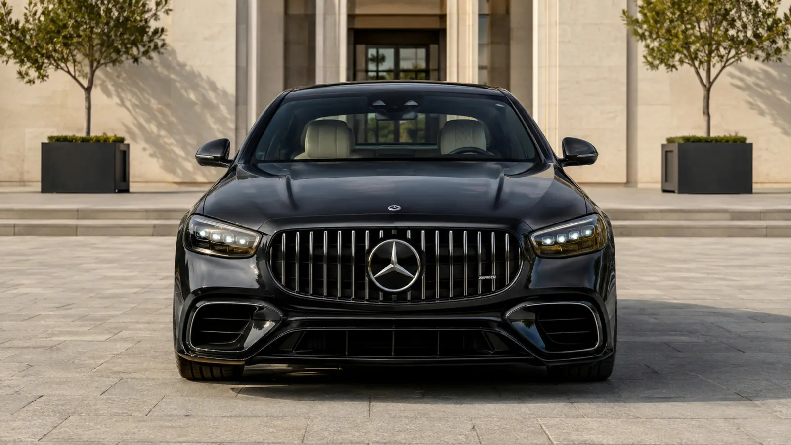 АВТО 1002824 чёрный Mercedes AMG S 63 строго спереди в светлом архитектурном дворе