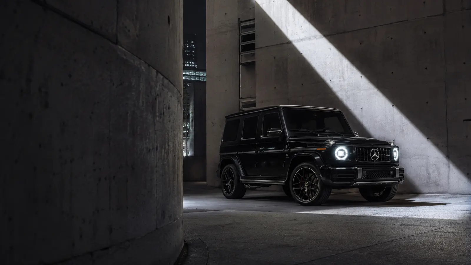 АВТО 1001963 чёрный Mercedes G-класс в луче света среди бетонной архитектуры