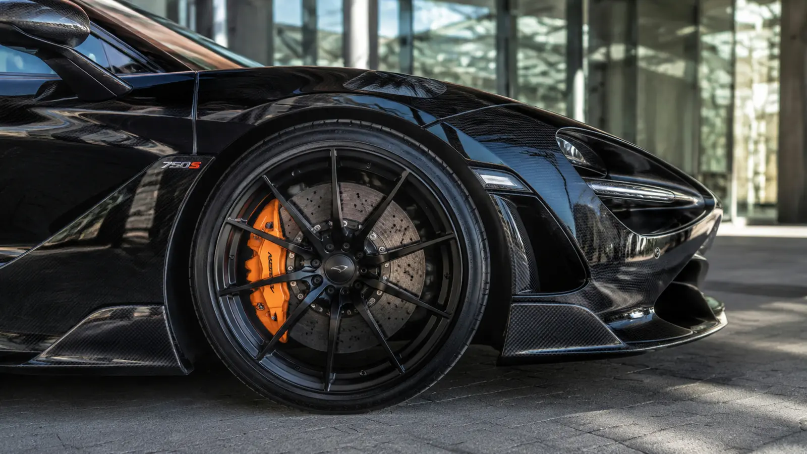 АВТО 1002902 крупное карбоновое колесо McLaren 750S у городского павильона