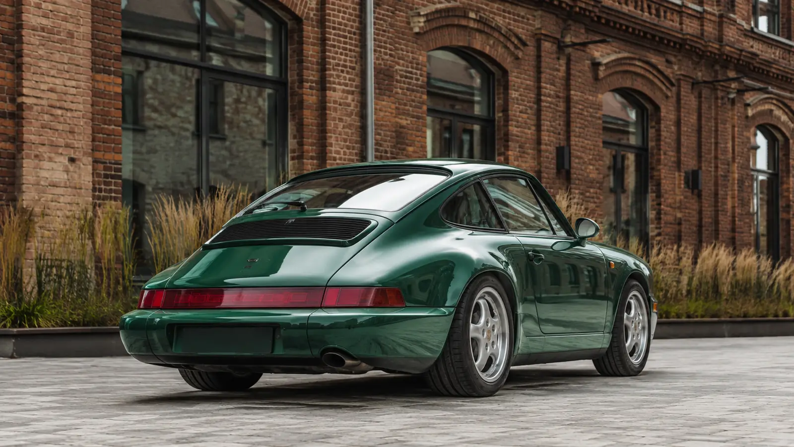 АВТО 1002294 зелёный Porsche 911 поколения 964 крупно у кирпичной архитектуры