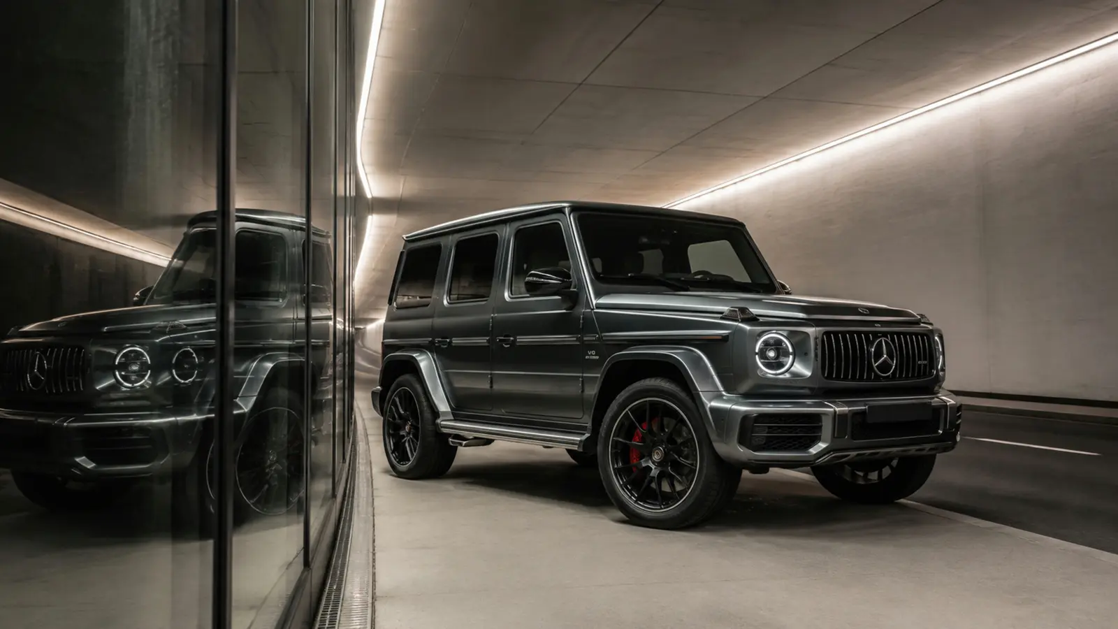 АВТО 1003251 графитовый Mercedes-AMG G 63 крупно отражение в стеклянном фасаде