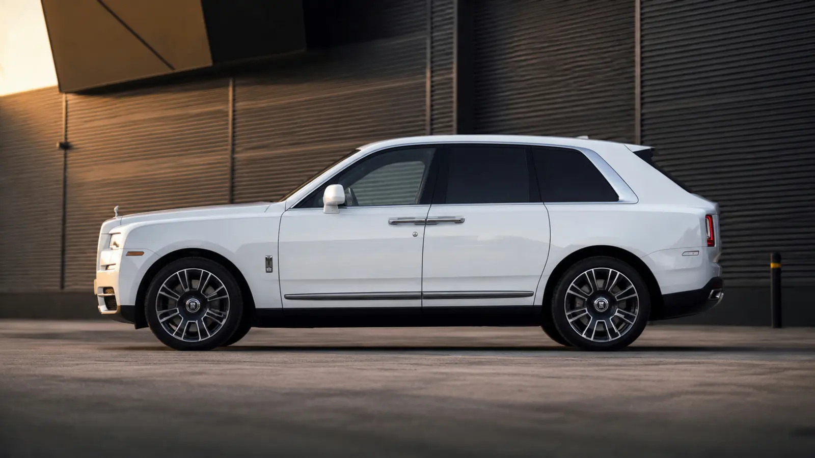 АВТО 1003031 белый Rolls-Royce Cullinan цельный боковой профиль у современной логистической архитектуры