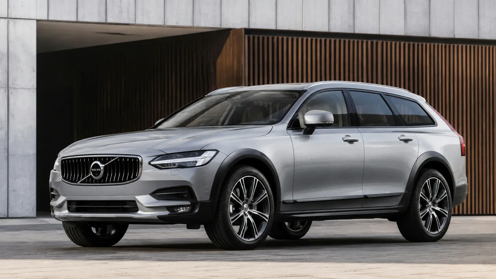 АВТО 1003065 серебристый Volvo V90 Cross Country крупный низкий ракурс у геометричного фасада