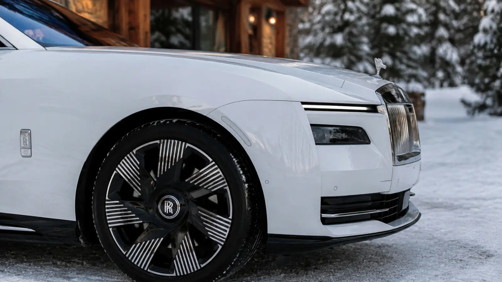 АВТО 1002974 белый Rolls-Royce Spectre диск и переднее крыло крупным планом на заснеженной дороге у шале