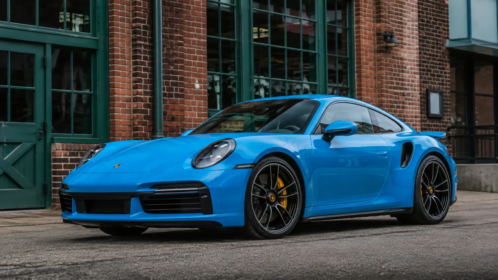 АВТО 1002204 голубой Porsche 911 Turbo S крупно у кирпичной архитектуры
