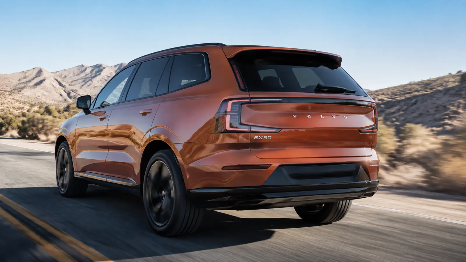 АВТО 1002788 оранжевый Volvo EX90 крупно на сухой пустынной дороге