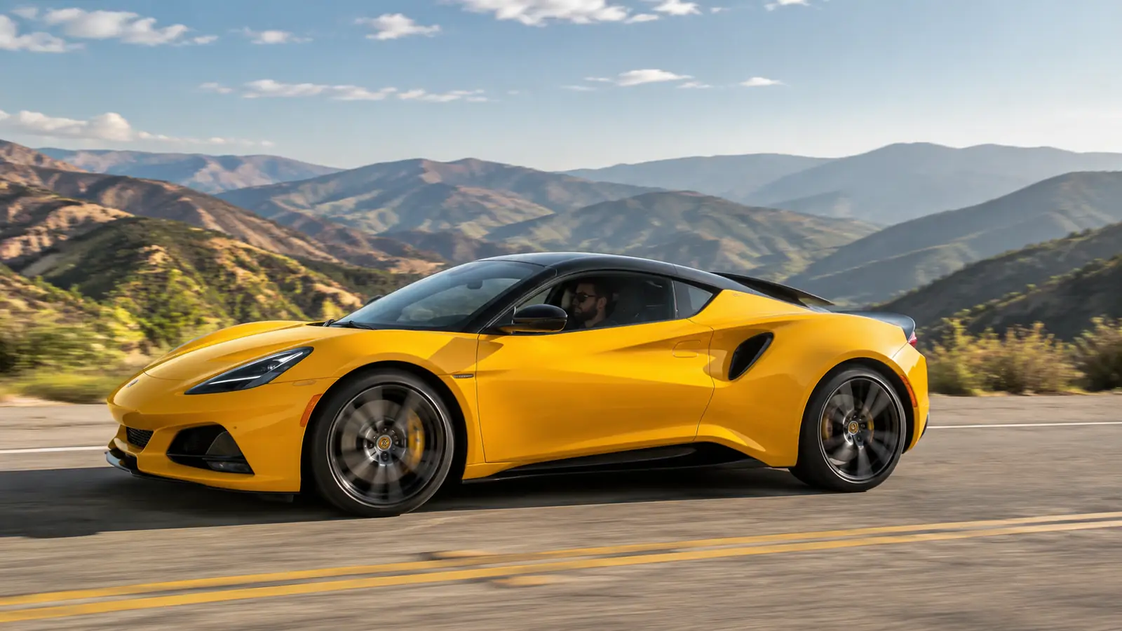 АВТО 1002485 жёлтый Lotus Emira на дороге через холмы